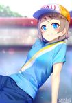  artist_name baseball_cap blue_eyes blurry blush brown_hair commentary_request depth_of_field grin hat headwear_writing looking_at_viewer love_live! love_live!_sunshine!! marshall_(wahooo) shirt short_hair short_sleeves smile solo t-shirt watanabe_you 