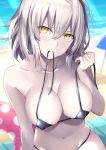  1girl absurdres beach bikini black_bikini blurry blurry_background blush breasts collarbone day eyebrows_visible_through_hair fate/grand_order fate_(series) hair_between_eyes head_tilt highres innertube jeanne_d&#039;arc_(alter_swimsuit_berserker) jeanne_d&#039;arc_(fate)_(all) large_breasts looking_at_viewer mouth_hold navel outdoors rin_yuu shiny shiny_skin short_hair silver sitting solo sunlight swimsuit undersized_clothes untied untied_bikini yellow_eyes 