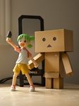  black_eyes box cardboard_box danboo figure full_body green_eyes green_hair minimized multicolored_shirt open_mouth photo revoltech shirt shorts t-shirt triangle_mouth yotsubato! 