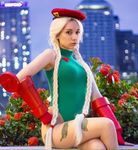  beke_(cosplayer) blonde_hair cammy_white city cosplay flower hat leotard long_hair looking_at_viewer night outdoor rose scar sitting street_fighter twintails 