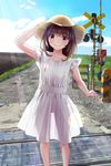  arm_up bangs blush brown_eyes brown_hair chikuwa_(odennabe) closed_mouth commentary_request day dress feet_out_of_frame grass gravel hand_on_headwear hat highres lens_flare light_rays long_hair looking_at_viewer original outdoors railroad_crossing see-through_silhouette short_sleeves smile solo standing sun_hat sunbeam sundress sunlight white_dress 