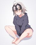  ahoge bangs bare_legs barefoot between_legs blush breasts closed_mouth commentary_request eyebrows_visible_through_hair eyes_visible_through_hair fate/grand_order fate_(series) feet_together full_body grey_background grey_sweater hand_between_legs highres hood hood_down hooded_sweater jeanne_d'arc_(alter)_(fate) jeanne_d'arc_(fate)_(all) long_sleeves looking_at_viewer medium_breasts pout shadow short_hair silver_hair simple_background sitting solo spicy_moo sweater yellow_eyes 