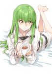  bangs barefoot c.c. code_geass creayus cup green_hair hood hoodie long_hair lying on_stomach parted_lips solo yellow_eyes 