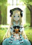  abigail_williams_(fate/grand_order) alternate_costume bangs beret black_bow black_hat blonde_hair blue_eyes blurry blurry_background blush bow closed_mouth dress eyebrows_visible_through_hair fate/grand_order fate_(series) frilled_dress frills grass hair_bow hat holding holding_stuffed_animal kazuma_muramasa long_hair looking_at_viewer nature outdoors parted_bangs sitting sleeveless sleeveless_dress smile solo striped stuffed_animal stuffed_toy sunlight teddy_bear tree vertical-striped_dress vertical_stripes very_long_hair white_bow 