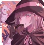  1girl bat_(animal) bow brown_cape brown_gloves cape danganronpa_(series) danganronpa_2:_goodbye_despair diaper doughnut ear_bow eating food galaga gloves hair_ornament hand_up hat heart highres ibushi_(kuyuru_29) long_sleeves medium_hair monomi_(danganronpa) nanami_chiaki orange_background pink_eyes pink_hair solo upper_body witch witch_hat 