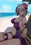  ahoge armband bangs beach beach_chair bikini breasts cleavage commentary_request copyright_name day eyebrows_visible_through_hair fate/grand_order fate_(series) flower hair_between_eyes hair_flower hair_ornament highres jeanne_d'arc_(alter)_(fate) jeanne_d'arc_(fate)_(all) kojima_(blue_stardust) large_breasts looking_at_viewer ocean palm_tree purple_bikini silver_hair solo swimsuit tree underboob yellow_eyes 