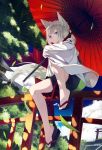  1girl animal_ears bangs clog_sandals closed_mouth grey_hair highres long_sleeves looking_at_viewer nagishiro_mito oriental_umbrella outdoors short_hair shorts silver_eyes sitting sitting_on_object smile solo tail torii tree umbrella 