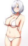  1girl absurdres arms_behind_back bikini blue_eyes blush breasts cleavage collarbone embarrassed hair_ornament hair_over_one_eye hairclip hamakaze_(kantai_collection) highres kantai_collection kusahagane large_breasts looking_at_viewer navel short_hair silver_hair simple_background skindentation solo swimsuit upper_body white_background white_bikini 
