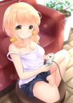  &gt;:) 1girl absurdres ahoge bangs barefoot black_shorts blonde_hair blurry blurry_background blush breasts camisole cleavage closed_mouth commentary_request controller couch crossed_legs depth_of_field eyebrows_visible_through_hair full_body game_controller hair_ornament hair_scrunchie highres holding inahori indoors long_hair low_twintails medium_breasts original plant potted_plant scrunchie short_shorts shorts sitting smile solo strap_slip twintails v-shaped_eyebrows white_camisole wooden_floor yellow_scrunchie 