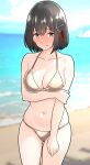  1girl alternate_costume arm_under_breasts bare_arms beach bikini black_hair blue_sky blurry blurry_background blush breasts brown_eyes cleavage closed_mouth cloud collarbone day embarrassed full-face_blush furaggu_(frag_0416) gold_bikini grabbing_own_arm haguro_(kancolle) hair_between_eyes hair_ornament highres kantai_collection large_breasts medium_breasts navel ocean outdoors short_hair sky solo standing swimsuit 