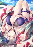  1girl artoria_pendragon_(all) artoria_pendragon_(lancer_alter) bangs bare_shoulders beach bikini black_bikini blonde_hair blush braid breasts cape cleavage fate/grand_order fate_(series) flower french_braid hair_between_eyes hair_flower hair_ornament halterneck highres hirasawa_seiji horns huge_breasts knees_up long_hair looking_at_viewer lying navel o-ring ocean on_back open_mouth parted_lips sidelocks solo swimsuit thigh_strap thighs yellow_eyes 