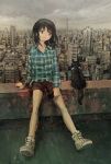  1girl bare_legs black_hair brown_eyes cat cityscape cloud cloudy_sky collared_shirt commentary day flannel highres holding holding_phone long_hair long_sleeves original outdoors overcast phone rooftop shirt shoes shorts sitting sky smile sneakers tokunaga_akimasa untucked_shirt 