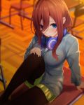  1girl arm_support bangs black_legwear blue_cardigan blue_eyes blush breasts brown_hair cardigan chair commentary_request desk feet_out_of_frame go-toubun_no_hanayome green_skirt hair_between_eyes headphones headphones_around_neck highres indoors knee_up long_hair long_sleeves looking_at_viewer medium_breasts miniskirt nakano_miku nigo_(aozoragarou) pantyhose pleated_skirt school_desk shadow sidelocks sitting skirt smile solo 