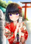  1girl black_hair blurry blurry_background blush closed_mouth commentary_request day depth_of_field floral_print flower hair_flower hair_ornament hands_up highres holding japanese_clothes kimono obi original outdoors print_kimono purple_eyes red_flower red_kimono sash short_hair smile solo taiki_ken torii upper_body wide_sleeves 