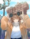  1girl absurdres ahoge alternate_costume arms_up blue_sky brown_coat brown_hair building chicken99 cloud coat commentary_request cowboy_shot day disneyland double_bun fur-trimmed_coat fur_trim highres kantai_collection kongou_(kantai_collection) lamppost long_hair looking_at_viewer outdoors purple_eyes road_sign sign sky solo sweater upper_body white_sweater 