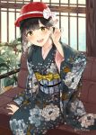  1girl :d arm_support bangs black_kimono blush bow commentary_request couch eyebrows_visible_through_hair floral_print hair_tucking hand_up hat hat_bow indoors japanese_clothes kimono long_sleeves looking_at_viewer miyabi_akino obi on_couch open_mouth original plant potted_plant print_kimono red_headwear sash sitting smile solo twitter_username upper_teeth white_bow wide_sleeves yellow_eyes 