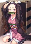  1girl arms_up bandages bit_gag black_hair black_legwear box brown_hair forehead gag gradient_hair hands_on_own_head haori highres japanese_clothes kamado_nezuko kimetsu_no_yaiba kimono kneehighs long_hair long_sleeves looking_at_viewer multicolored_hair obi on_floor pink_kimono purple_eyes r_o_ha sash sitting solo tears two-tone_hair wavy_hair 