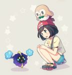  1girl bag bangs beanie black_hair blush commentary_request cosmog eyebrows_visible_through_hair eyelashes gen_7_pokemon green_shorts hands_on_own_knees hat kurochiroko legendary_pokemon looking_down open_mouth pokemon pokemon_(creature) pokemon_(game) pokemon_sm red_headwear rowlet selene_(pokemon) shirt shoes short_hair short_sleeves shorts shoulder_bag squatting star_(symbol) tongue upper_teeth yellow_shirt 