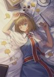  1girl alice_margatroid arms_up bangs blonde_hair blue_dress blue_eyes book book_stack capelet checkerboard_cookie cookie cowboy_shot cup dress food ginkgo_leaf hairband hand_on_own_forehead highres holding_cookie lolita_hairband looking_at_viewer lying on_back on_bed one_eye_closed ookashippo open_book parted_lips sash saucer short_hair solo teacup touhou white_capelet 