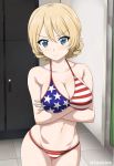  1girl american_flag_bikini arms_under_breasts bangs bare_shoulders bikini blonde_hair blue_eyes blush braid breasts cleavage closed_mouth collarbone commentary_request cowboy_shot crossed_arms darjeeling_(girls_und_panzer) eyebrows_visible_through_hair flag_print girls_und_panzer groin hair_between_eyes indoors inoshira large_breasts locker locker_room looking_at_viewer navel shiny shiny_hair solo swept_bangs swimsuit thighs twitter_username v-shaped_eyebrows 
