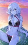  1girl absurdres ahoge bangs bikini black_bikini black_choker blush bon_ice breasts choker cleavage eyebrows eyebrows_visible_through_hair fate/grand_order fate_(series) hair_between_eyes highres horizon jeanne_d&#039;arc_(alter_swimsuit_berserker) jeanne_d&#039;arc_(fate)_(all) large_breasts lifebuoy long_hair looking_at_viewer navel nipi27 o-ring o-ring_bikini o-ring_top silver_hair smile solo sunset swimsuit very_long_hair water wet wet_clothes wet_hair wet_swimsuit yellow_eyes 