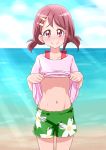  1girl asymmetrical_bangs bangs bare_legs beach belly blush brown_hair collarbone commentary_request cowboy_shot day floral_print flower green_shorts groin hair_flower hair_ornament hairpin hanadera_nodoka healin&#039;_good_precure highres light_rays navel nose_blush ocean outdoors pink_eyes pink_shirt precure rin_takanashi_glacies sand shiny shiny_skin shirt shirt_lift short_hair short_twintails shorts smile solo stomach toned twintails 