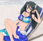  1girl beach bikini black_hair blue_bikini blue_eyes breasts chair collarbone commentary_request feet_out_of_frame floral_print groin highres isuzu_(kantai_collection) kantai_collection large_breasts long_hair looking_at_viewer lounge_chair navel sarong sitting smile solo swimsuit tori_knkr twintails 