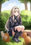  1girl absurdres an-94_(girls_frontline) bag black_footwear black_gloves black_jacket blue_eyes boots bush cat daisy_cutter day girls_frontline gloves highres jacket long_hair outdoors paper_bag platinum_blonde_hair solo squatting tactical_clothes thigh_strap tree 