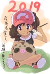  1girl 2019 :p bangs baseball_cap brown_eyes brown_hair closed_mouth collarbone commentary_request elaine_(pokemon) eyelashes gen_2_pokemon grass hat highres holding holding_paintbrush looking_down ohashi_aito paintbrush painting pokemon pokemon_(creature) pokemon_(game) pokemon_lgpe shirt shoes short_sleeves sitting smile sneakers swinub tongue tongue_out translation_request white_footwear 