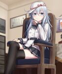  1girl armchair belt black_legwear black_skirt blue_eyes blurry blurry_background blush chair closed_mouth crossed_legs eyebrows_visible_through_hair flat_cap hair_between_eyes hammer_and_sickle hat hibiki_(kancolle) highres indoors kantai_collection long_hair long_sleeves looking_at_viewer pleated_skirt silver_hair sitting skirt smile solo thighhighs verniy_(kancolle) white_headwear yakob_labo 
