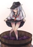  1girl anchor_symbol bare_legs barefoot black_headwear black_sailor_collar black_skirt blue_eyes blush eyebrows_visible_through_hair flat_cap food fruit grape_stomping grapes hair_between_eyes hat hibiki_(kancolle) highres kantai_collection kuuru_(kuuru-n) long_hair long_sleeves neckerchief parted_lips pleated_skirt red_neckwear sailor_collar school_uniform serafuku silver_hair skirt solo 