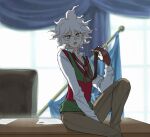  1boy bangs blurry blurry_background blush brown_neckwear brown_pants collarbone collared_shirt commentary danganronpa_(series) danganronpa_2:_goodbye_despair desk feet_out_of_frame green_vest grey_eyes hair_between_eyes hand_up knee_up komaeda_nagito long_sleeves looking_at_viewer male_focus official_alternate_costume open_mouth pants paper red_vest shirt sitting solo upper_teeth vest white_hair yandr4hope 