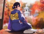  1girl arm_support autumn autumn_leaves bangs black_hair blue_kimono blurry blurry_background checkered_obi commentary_request cup day flower from_behind hair_between_eyes hair_bun hair_flower hair_ornament holding holding_leaf idolmaster idolmaster_shiny_colors japanese_clothes kimono leaf looking_at_viewer looking_back maple_leaf morino_rinze obi porch red_eyes sash short_hair sitting solo spung tabi teacup teapot yellow_sash yokozuwari 