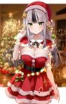  1girl bare_arms belt blurry breasts capelet christmas_lights cleavage cowboy_shot depth_of_field dress fur_trim green_eyes grey_hair hand_up hat highres large_breasts layered_dress long_hair looking_at_viewer mayo_(miyusa) multicolored_hair original red_dress red_headwear santa_costume santa_hat smile solo standing strapless strapless_dress two-tone_hair 