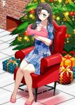  1boy 1girl arizona_(azur_lane) armchair azur_lane baby blue_dress blush brown_hair chair child christmas_ornaments christmas_tree closed_mouth commission crossed_arms dress fireplace full_body gift green_eyes highres knees_together_feet_apart legs mother_and_son second-party_source sitting sleeping slippers smile swaddled toy_bits 