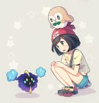  1girl bag bangs beanie black_hair blush commentary_request cosmog eyebrows_visible_through_hair eyelashes green_shorts hands_on_own_knees hat kurochiroko looking_down on_head open_mouth pokemon pokemon_(creature) pokemon_(game) pokemon_on_head pokemon_sm red_headwear rowlet selene_(pokemon) shirt shoes short_hair short_sleeves shorts shoulder_bag squatting star_(symbol) teeth tongue upper_teeth yellow_shirt 