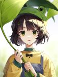  1girl :p absurdres aniroud bangs blue_eyes bow brown_hair copyright_request frog_hat green_eyes green_headwear hair_bow hair_ornament hairclip highres holding holding_leaf leaf long_sleeves looking_at_viewer shirt short_hair solo tongue tongue_out upper_body yellow_shirt 