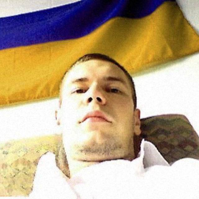 brown_hair closed_mouth indoors looking_at_viewer non-web_source off-topic photo_(medium) short_hair ugly_man ukrainian_flag upper_body very_short_hair