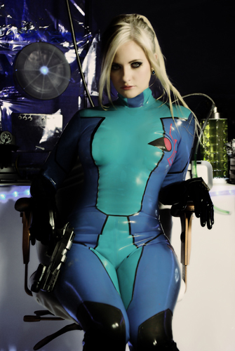 arm_support blonde_hair blue_bodysuit blue_eyes bodysuit breasts chair closed_mouth cosplay cowboy_shot earrings emblem expressionless eyelashes eyeliner eyeshadow gloves gun handgun high_ponytail holding holding_gun holding_weapon indoors jewelry latex legs_together lips lipstick long_hair looking_at_viewer lowres makeup medium_breasts metroid metroid:_zero_mission office_chair on_chair paralyzer photo pink_lipstick ponytail samus_aran samus_aran_(cosplay) shiny shiny_clothes sidelocks sitting skin_tight solo straight_hair stun_gun turtleneck weapon zero_suit