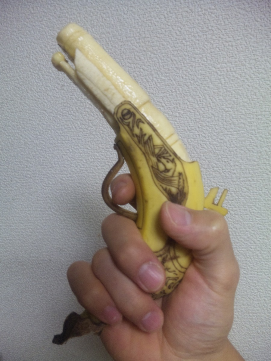 banana food fruit gun handgun highres holding photo pistol sculpture weapon y_yamaden