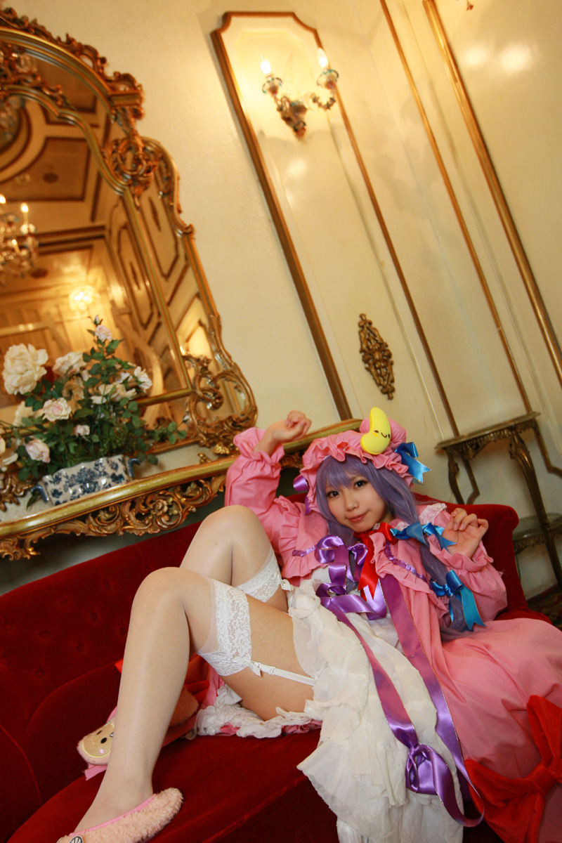 1girl asian cosplay couch crescent dress female garter_straps hat highres long_hair patchouli_knowledge photo purple_hair red_upholstery solo tenshi_myu thighhighs touhou