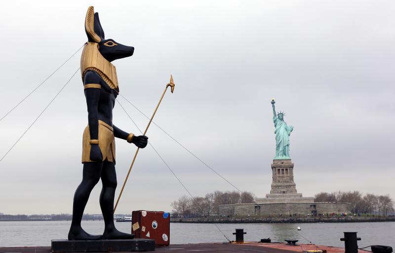 anubis canine deity jackal mammal new_york photo real sculpture standing statue statue_of_liberty suitcase unknown_artist what