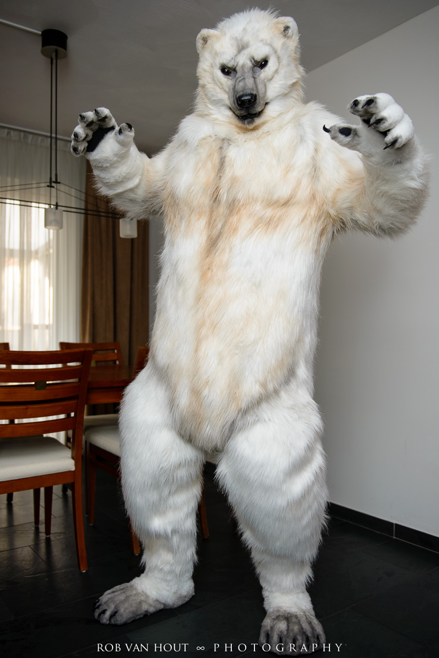 chair fursuit garrodor looking_at_viewer male mammal polar_bear pose real solo standing table text