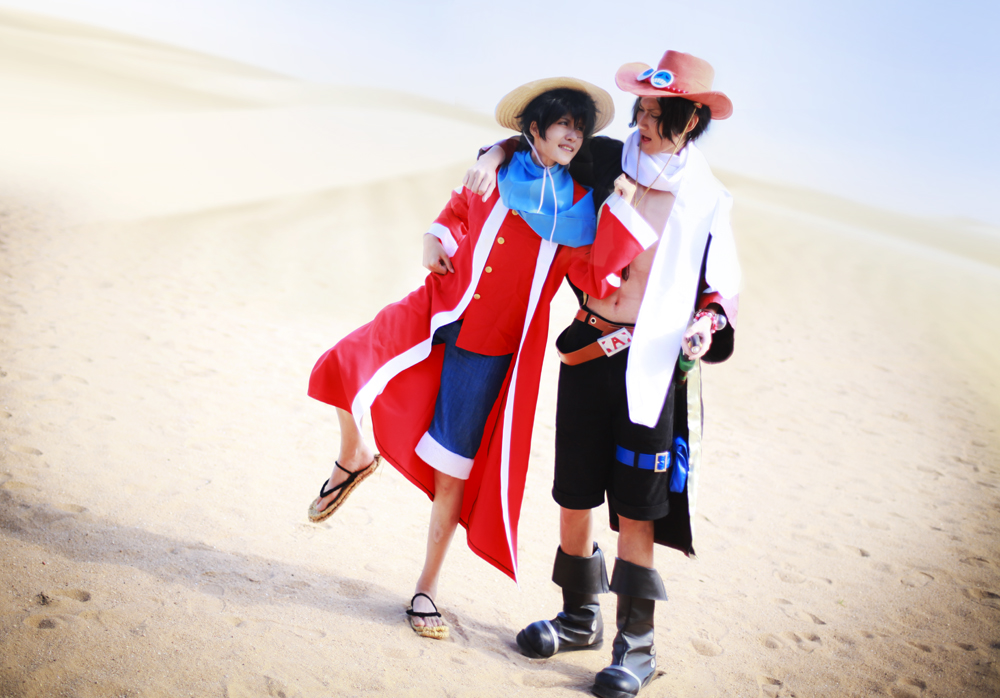 alabasta belt boots brothers cloak cosplay denim denim_shorts duo han-kouga hat monkey_d_luffy one_piece open_clothes open_shirt photo portgas_d_ace sand sandals scarf shirt shorts siblings stampede_string straw_hat thigh_strap vest