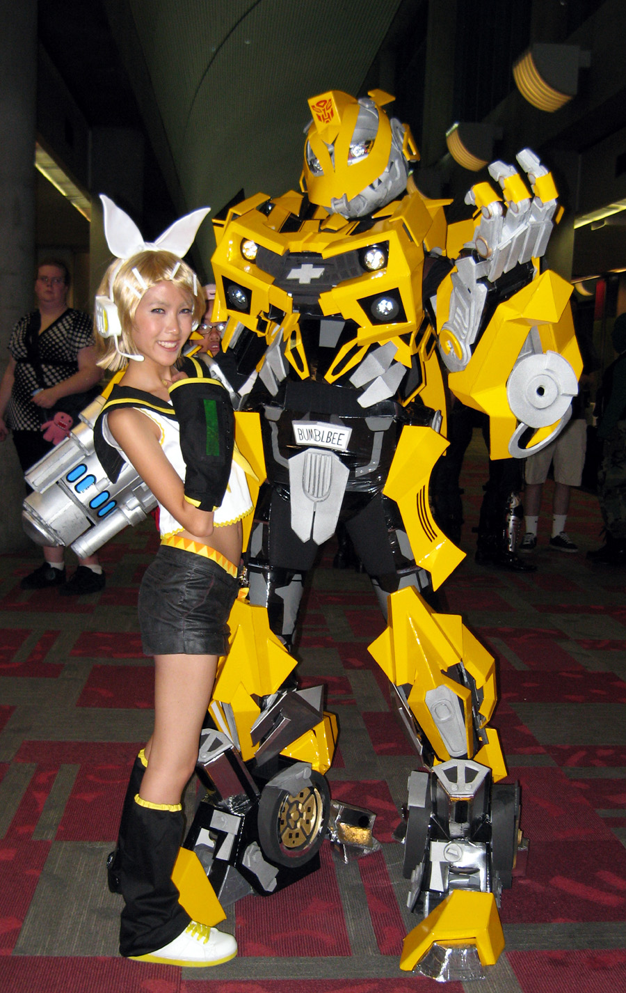 blonde_hair bow bumblebee cosplay couple hetero highres kagamine_rin mecha photo robot shorts transformers vocaloid yellow