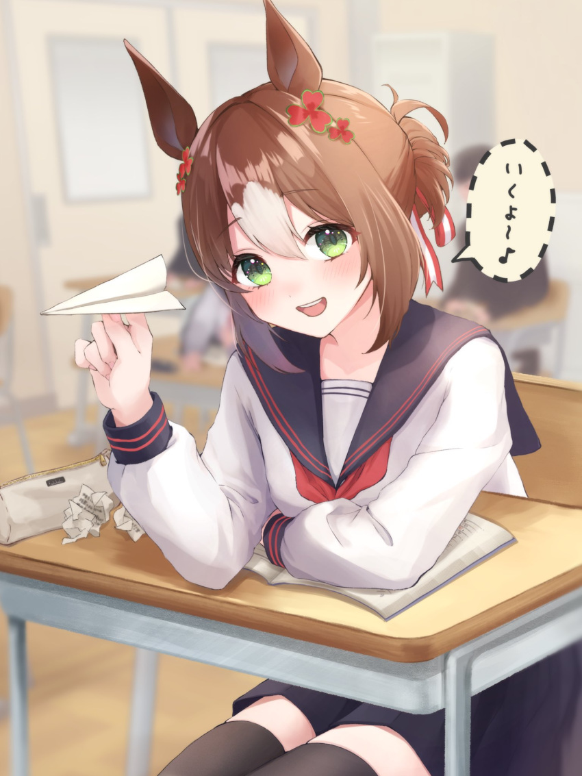 1girl animal_ears bangs black_legwear blue_skirt blurry blurry_background blush brown_hair chair clover_hair_ornament crumpled_paper desk fine_motion_(umamusume) green_eyes hair_bun hair_ornament highres horse_ears indoors long_sleeves medium_hair multicolored_hair neckerchief notebook open_mouth paper_airplane pencil_case red_neckerchief sailor_collar school_desk shirt sitting skirt smile solo speech_bubble thighhighs two-tone_hair umamusume white_shirt yamaro_emo_pvc