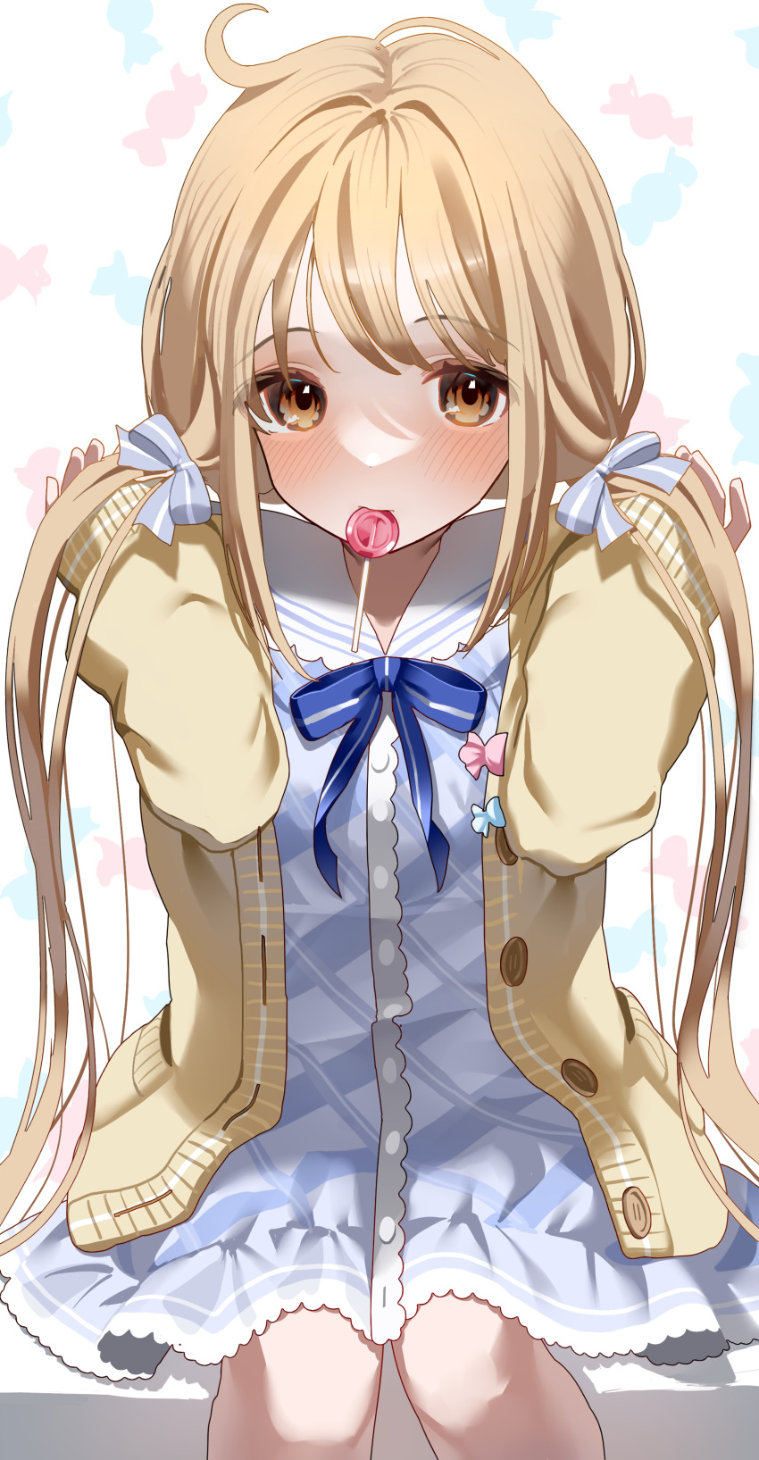 1girl absurdres blonde_hair blue_dress blush candy candy_print cardigan dress feet_out_of_frame food futaba_anzu hair_ribbon highres idolmaster idolmaster_cinderella_girls lollipop looking_at_viewer mouth_hold neck_ribbon ningen_mame patterned_background ribbon sailor_collar simple_background sitting sleeves_past_wrists solo twintails yellow_cardigan