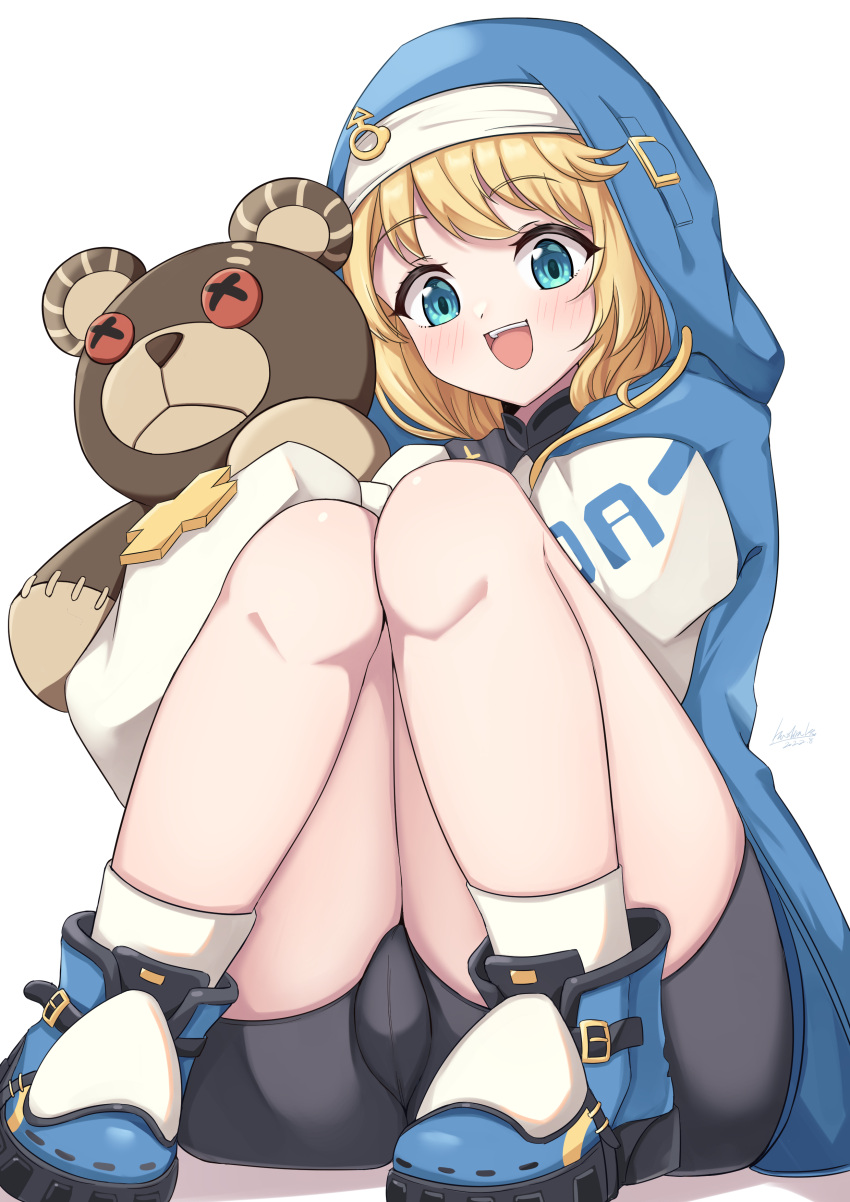 1girl :d absurdres bike_shorts blonde_hair blue_eyes blush bridget_(guilty_gear) bulge guilty_gear guilty_gear_strive hashira_14 highres hood hood_up hoodie long_sleeves male_focus open_mouth otoko_no_ko roger_(guilty_gear) simple_background sitting smile solo stuffed_animal stuffed_toy teddy_bear thighs transgender white_background