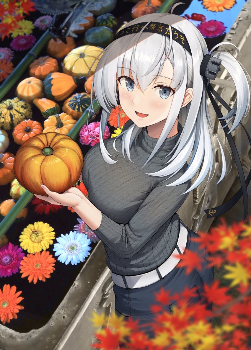 1girl alternate_costume autumn autumn_leaves black_headband black_pants blue_eyes blush breasts clothes_writing food grey_sweater hachimaki hair_between_eyes headband highres holding holding_food holding_vegetable ichikawa_feesu kantai_collection large_breasts long_hair long_sleeves one_side_up open_mouth pants photo_background pumpkin smile solo suzutsuki_(kancolle) sweater vegetable white_hair