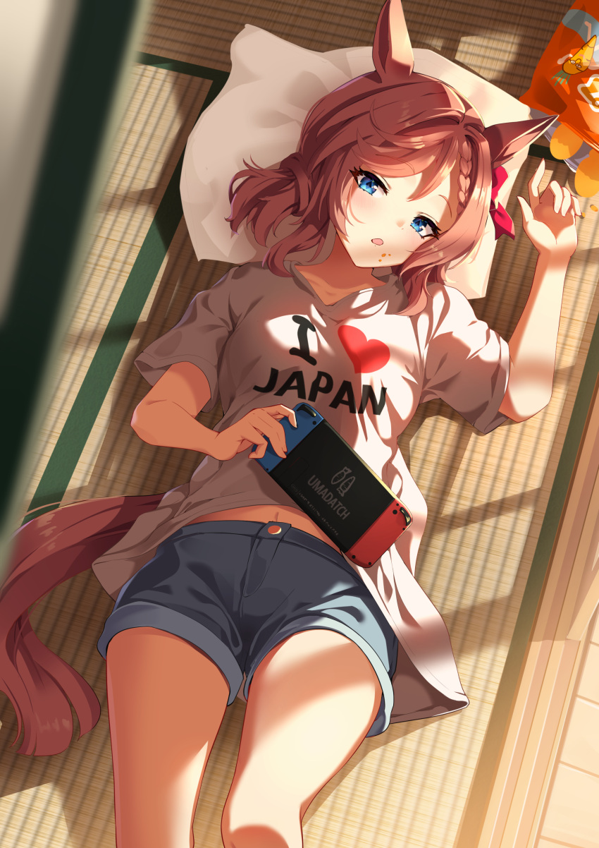 1girl absurdres animal_ears blue_eyes bow braid brown_hair collarbone commentary_request crumbs food food_on_face french_commentary hair_between_eyes handheld_game_console highres holding holding_handheld_game_console horse_ears horse_girl horse_tail looking_at_viewer lying midriff_peek navel nintendo_switch on_back open_mouth pillow shirt shorts solo sunny_(20597521) tail tatami umamusume venus_paques_(umamusume) white_shirt